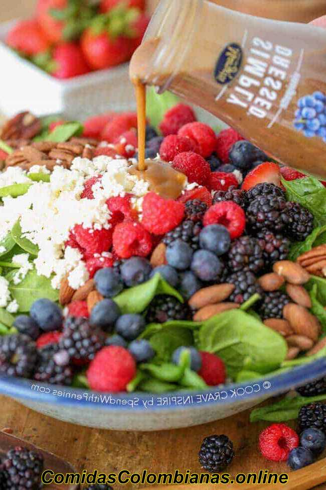 Verter el aderezo sobre un tazón de ensalada de espinacas con frutas y nueces