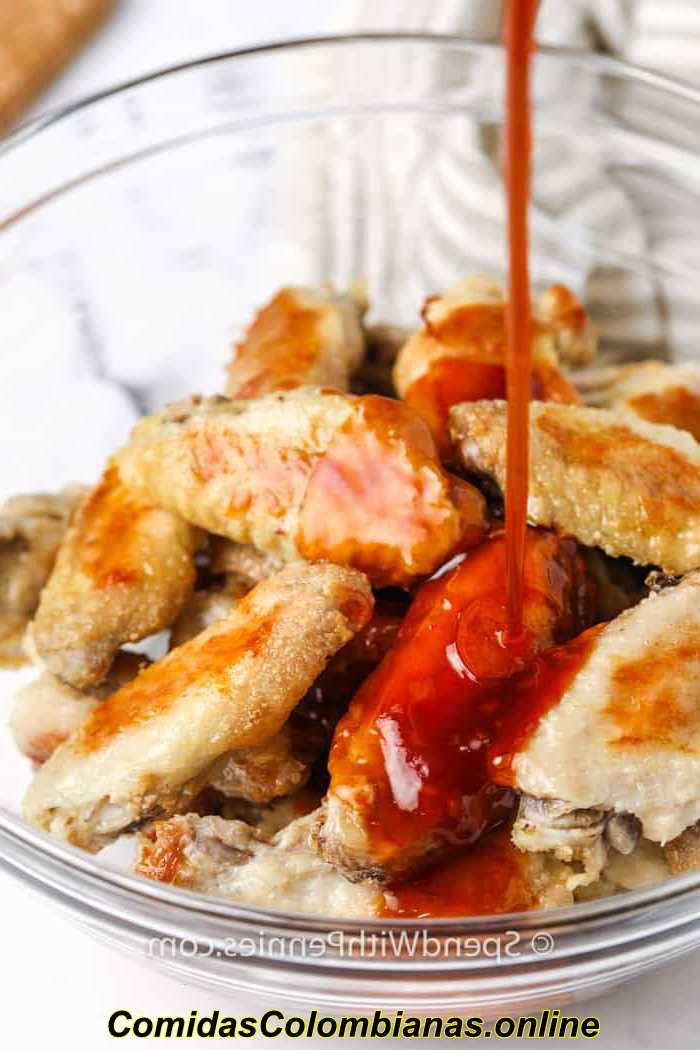 verter salsa en las alas para hacer Sticky Hot Chicken Wings