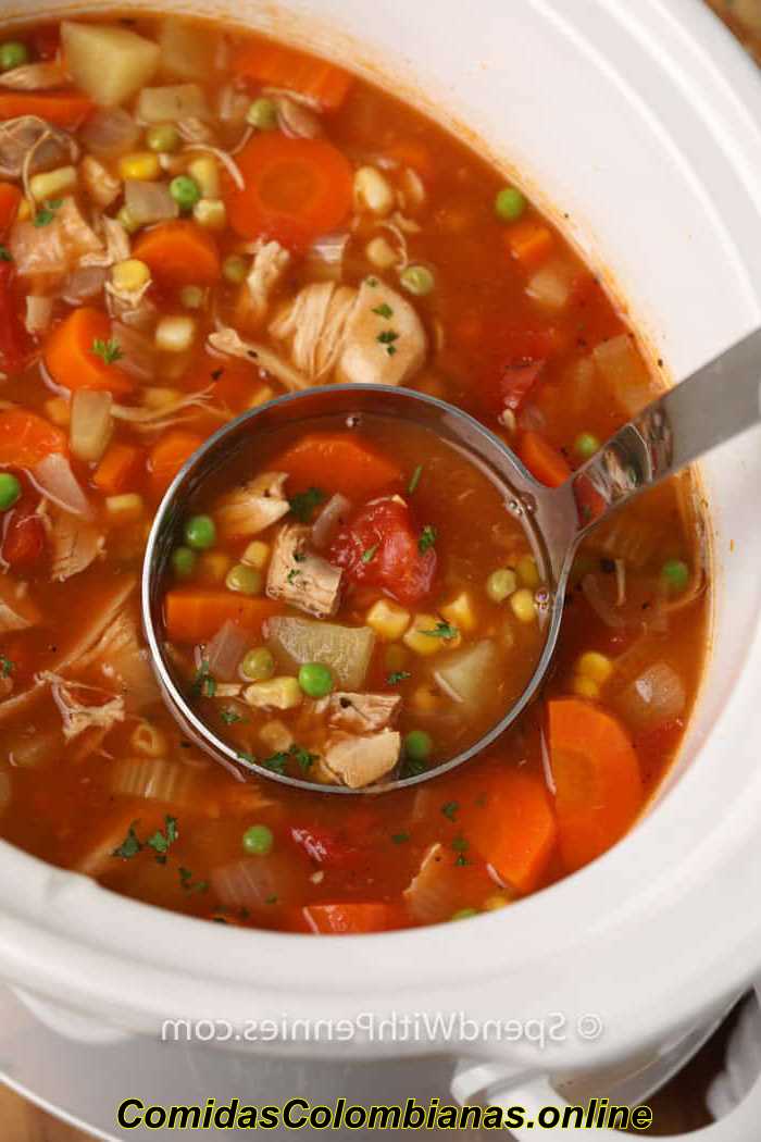 cucharón de sopa de verduras de pavo de cocción lenta en una olla de cocción lenta