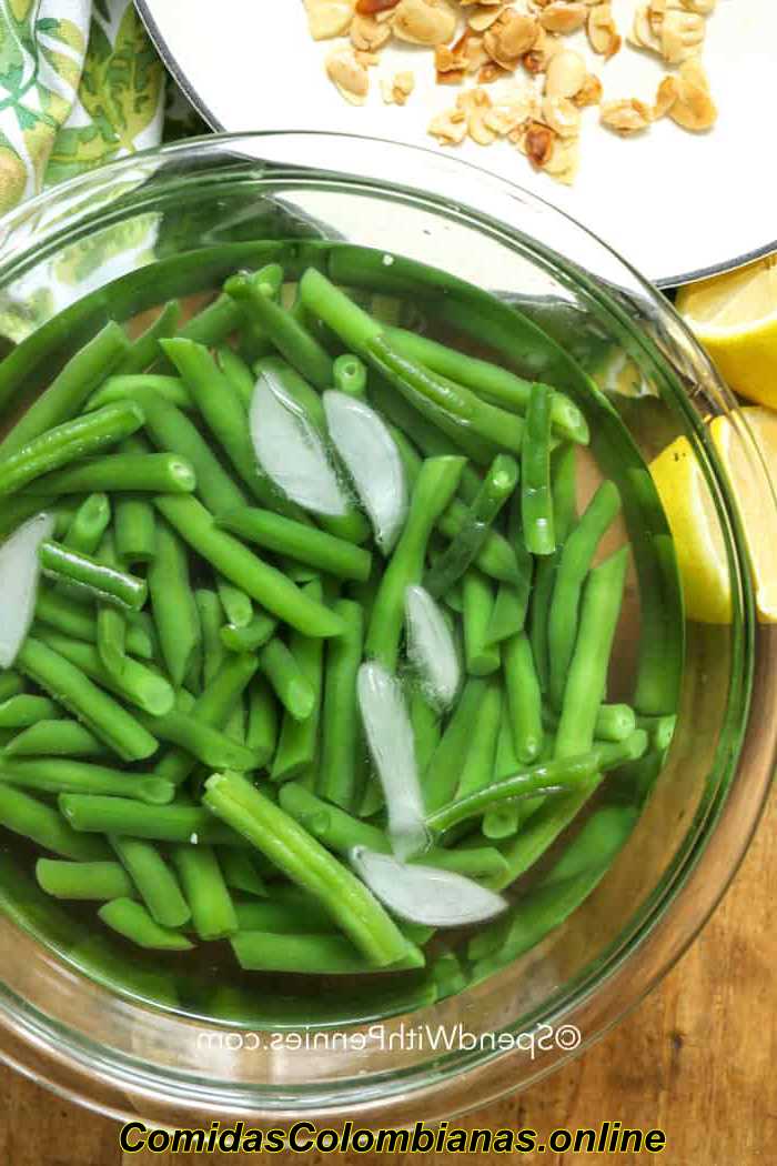 Judías verdes en agua helada en un recipiente transparente