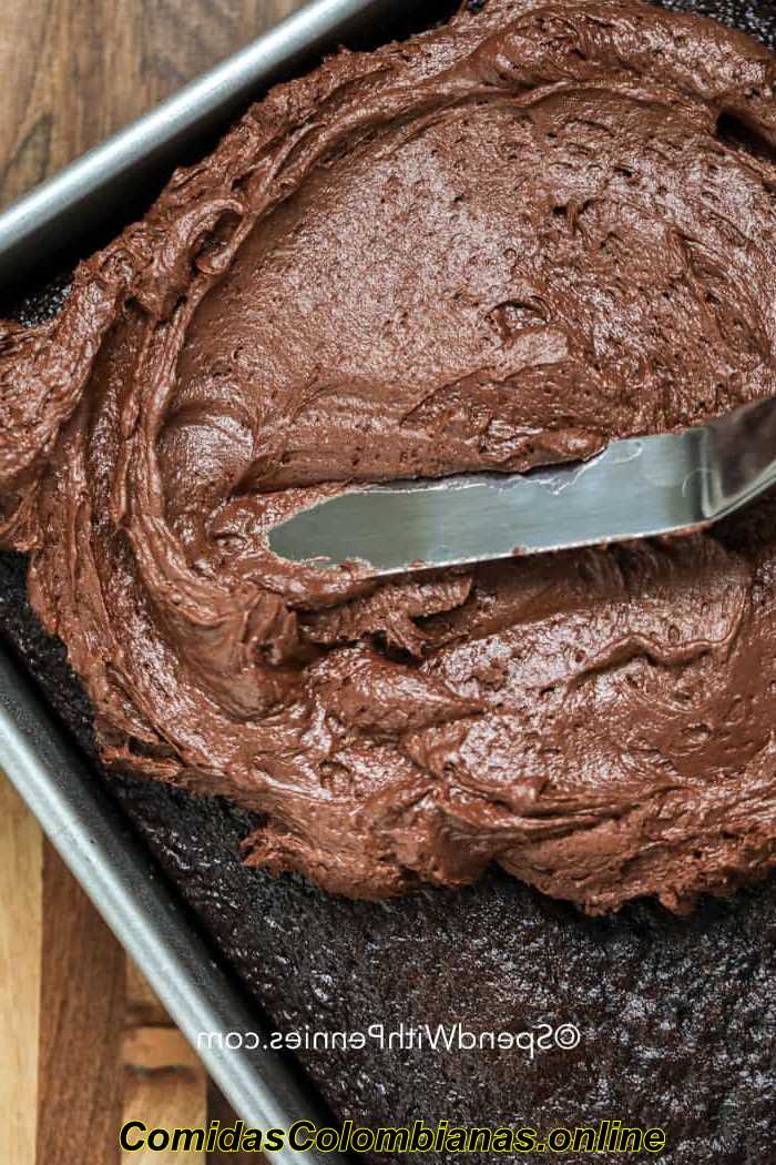 Espalhando cobertura de chocolate em um bolo de chocolate