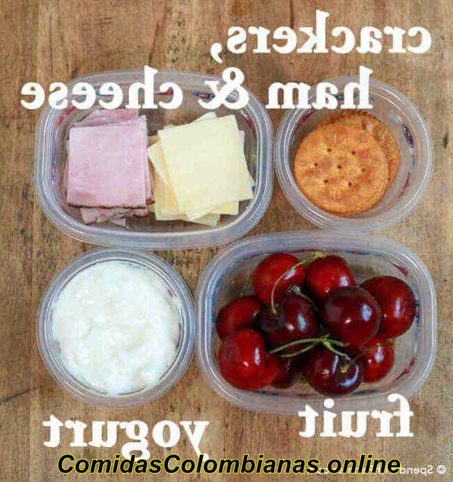 Fotografía cenital de galletas, cerezas, yogur, lonchas de jamón y queso