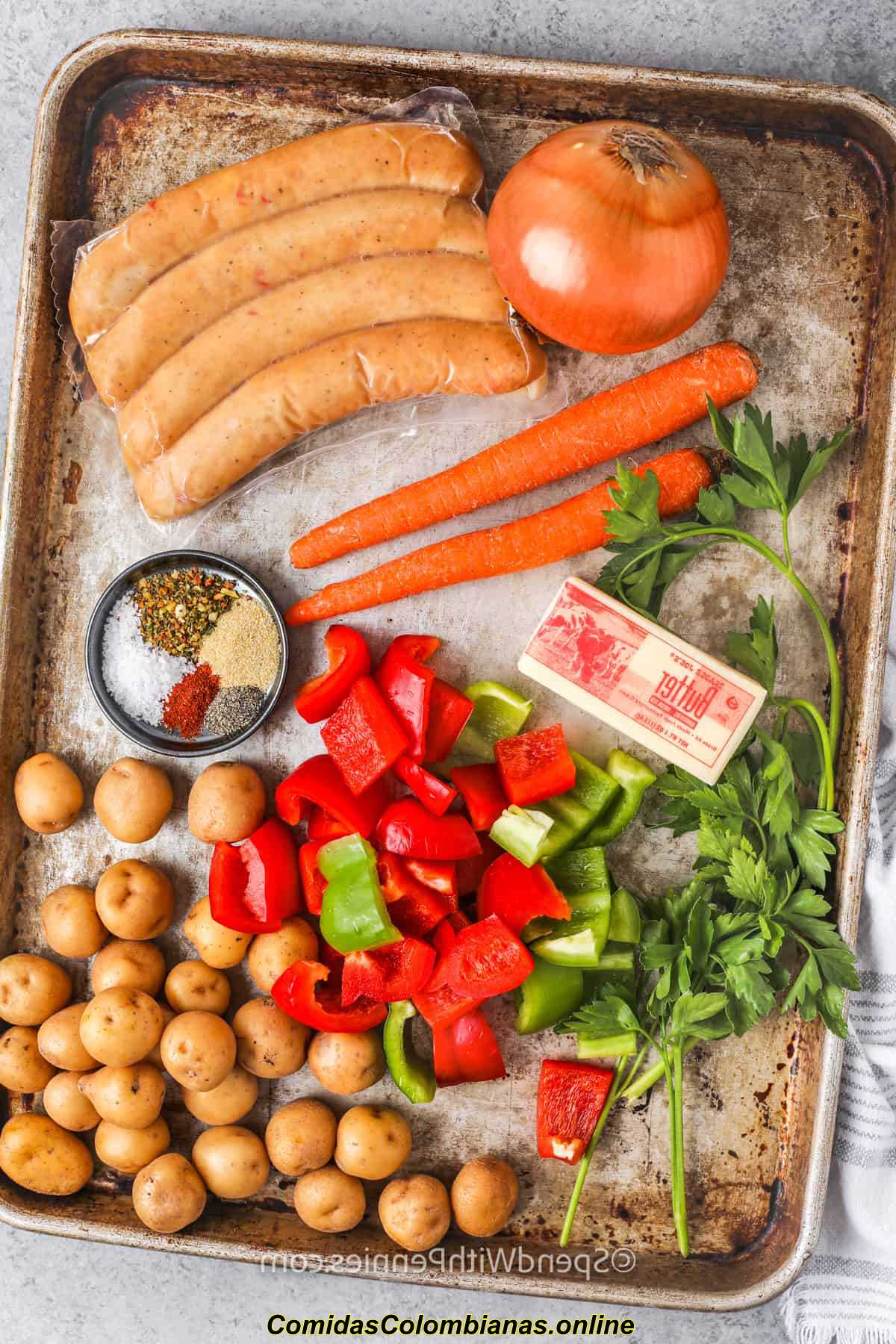 ingredientes para hacer paquetes de salchichas y vegetales en una bandeja para hornear