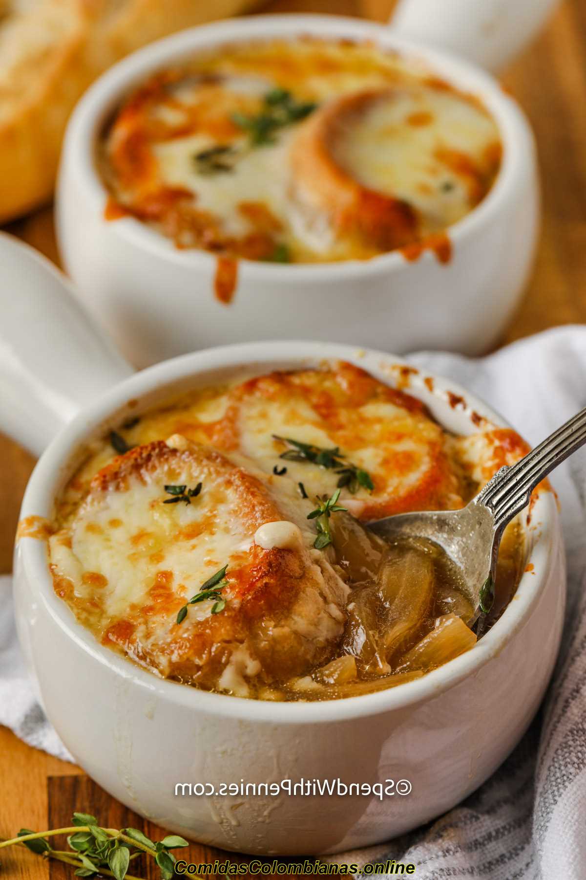 tazze di zuppa di cipolle francese fatta in casa con un cucchiaio in uno