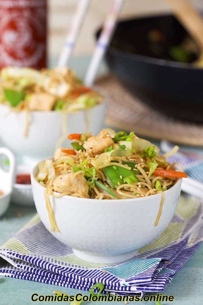 Chow mein de pollo en un tazón blanco con semillas de sésamo y cebollas verdes